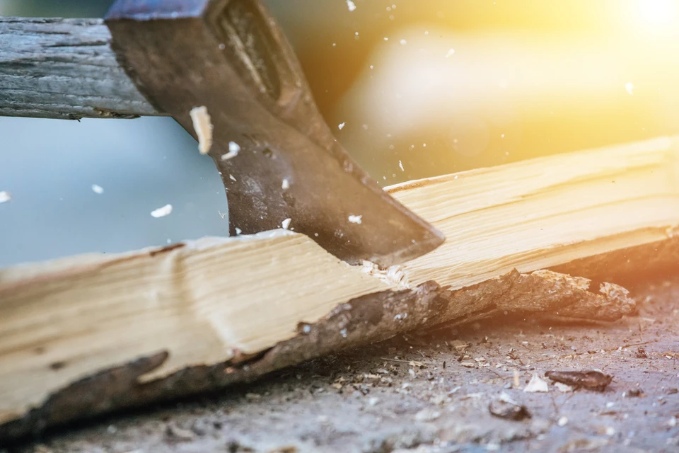 Atelier de menuiserie où un artisan utilise une herminette pour façonner une pièce de bois