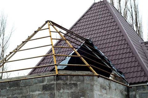 Chantier de construction résidentielle en cours avec ouvrier effectuant des travaux de toiture