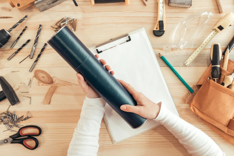 Atelier de menuiserie avec artisan tenant tube de colle ou mastic noir