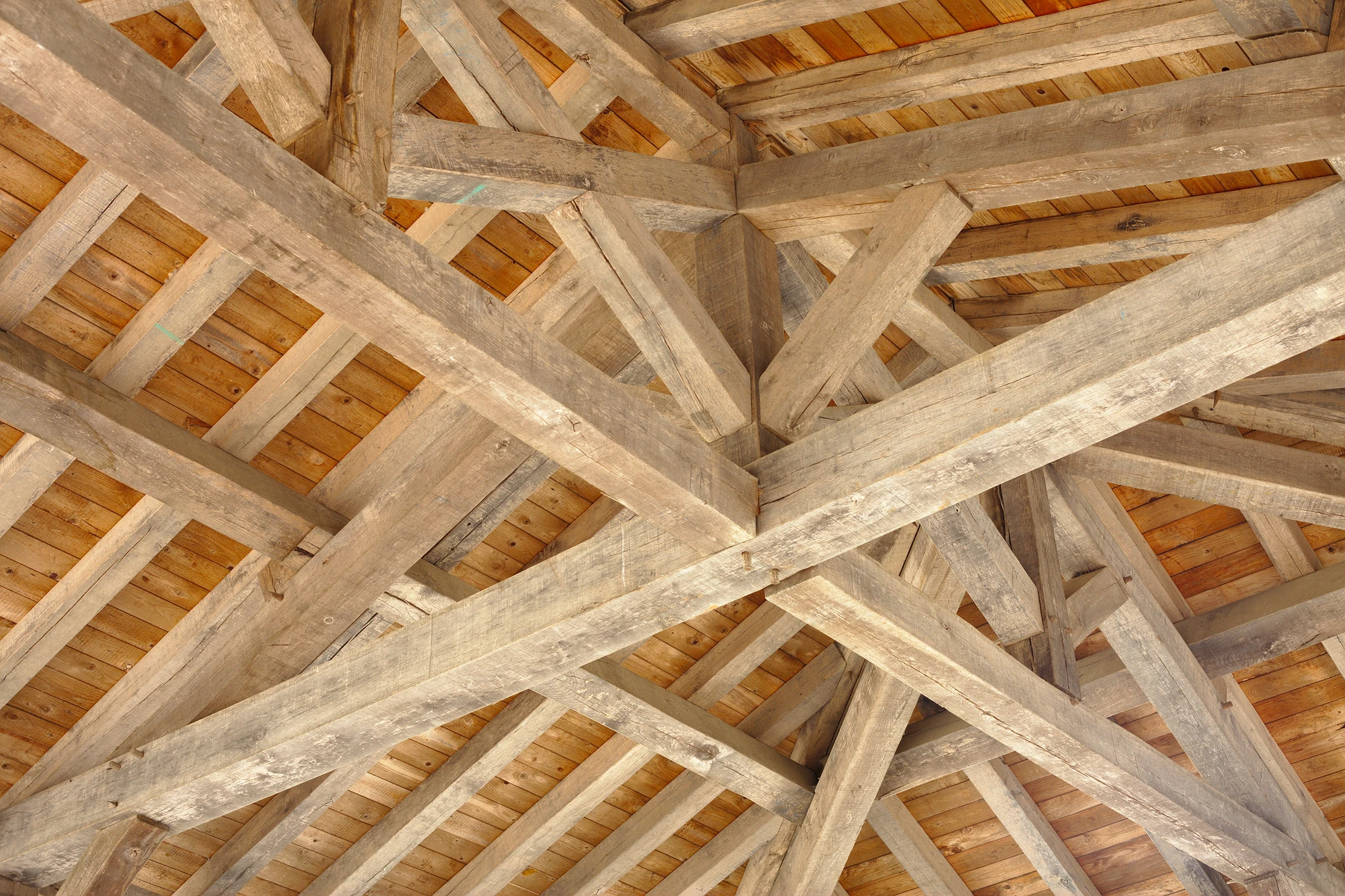 Atelier de menuiserie o&ugrave; un artisan utilise une herminette pour fa&ccedil;onner une pi&egrave;ce de bois